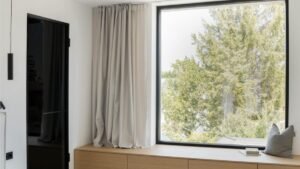 Chambre élégante avec grande fenêtre fixe sans ouverture sur un décor épuré.