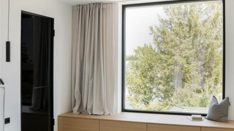 Chambre élégante avec grande fenêtre fixe sans ouverture sur un décor épuré.