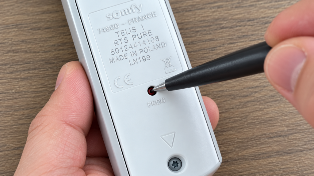 Appui sur la touche PROG au dos d’une télécommande Somfy Telis 1 RTS avec la pointe d’un stylo
